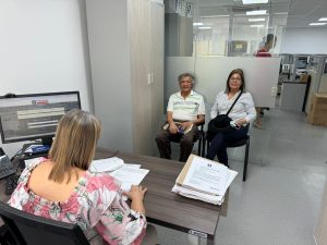 En la imagen se observan dos personas sentadas recibiendo atención por parte de una funcionaria de la Fiscalía General de la Nación