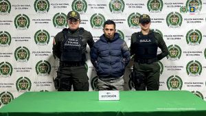 En la imagen aparece el capturado de pie en compañía de d dos uniformados de la Policía Nacional