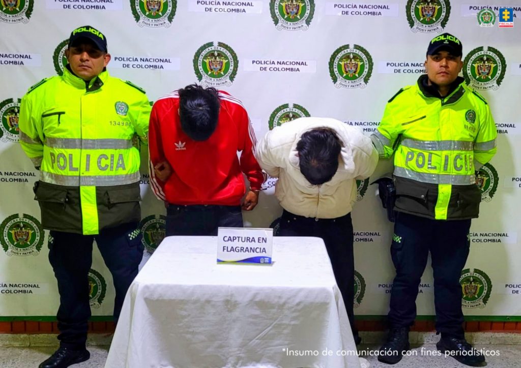 En la fotografía se observan cuatro personas dos de ellas los capturados y dos los uniformados de la Policía Nacional.