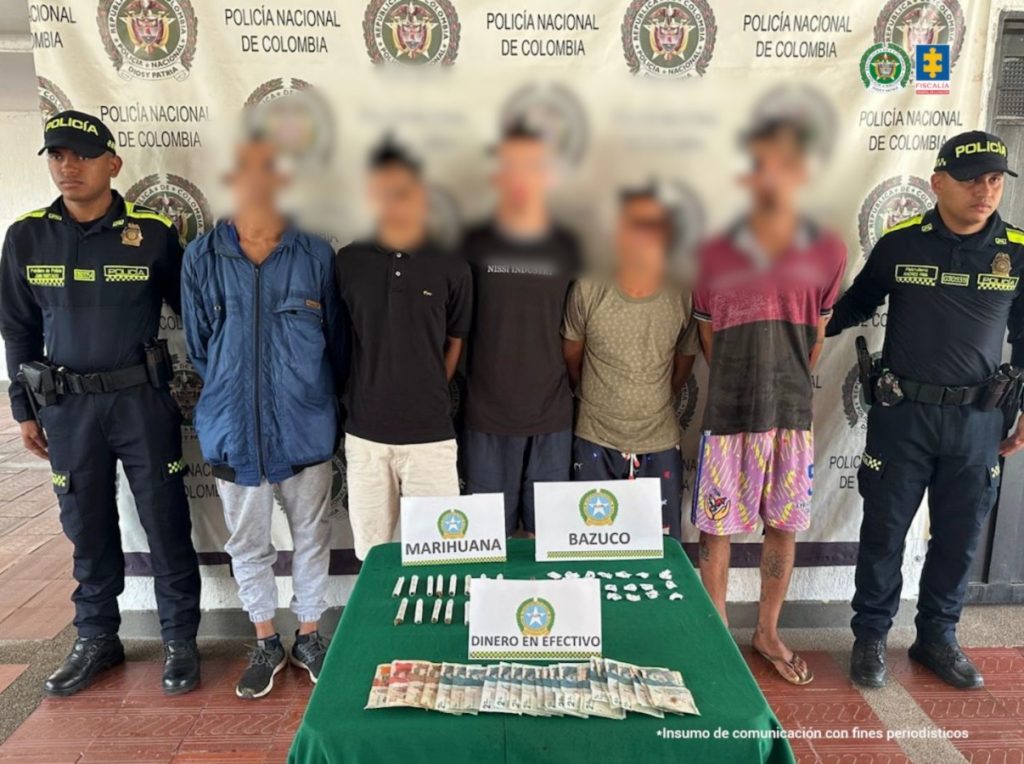 En la imagen aparecen los procesados, de frente, en medio de una pareja de servidores de la Policía Nacional. También, se observa el dinero en efectivo, papeletas de bazuco y cigarrillos de marihuana que fueron incautadas en diligencias de registro y allanamiento.