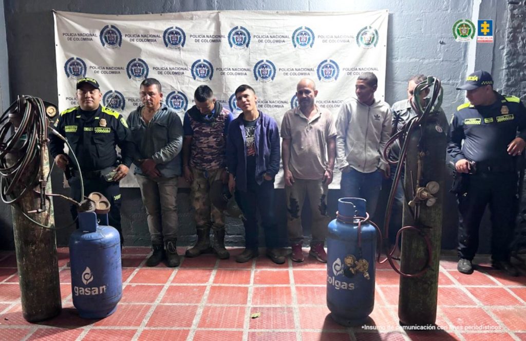 En la imagen aparecen seis procesados, en medio de una pareja de servidores de la Policía Nacional. También, se observan los elementos incautados durante el procedimiento de captura.