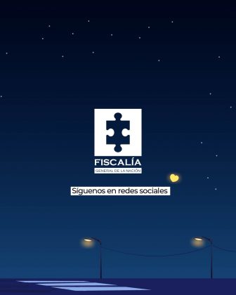 La imagen tiene un fondo azul oscuro que simula un cielo nocturno con varias estrellas. En la parte inferior se observan postes de luz encendidos y una silueta de calle iluminada. En el centro aparece el logotipo de la Fiscalía General de la Nación (pieza de rompecabezas blanca en un recuadro), acompañado del texto: “Síguenos en redes sociales” A la derecha del logo se ve un ícono en forma de corazón amarillo brillante, que resalta como un punto de luz en el diseño.