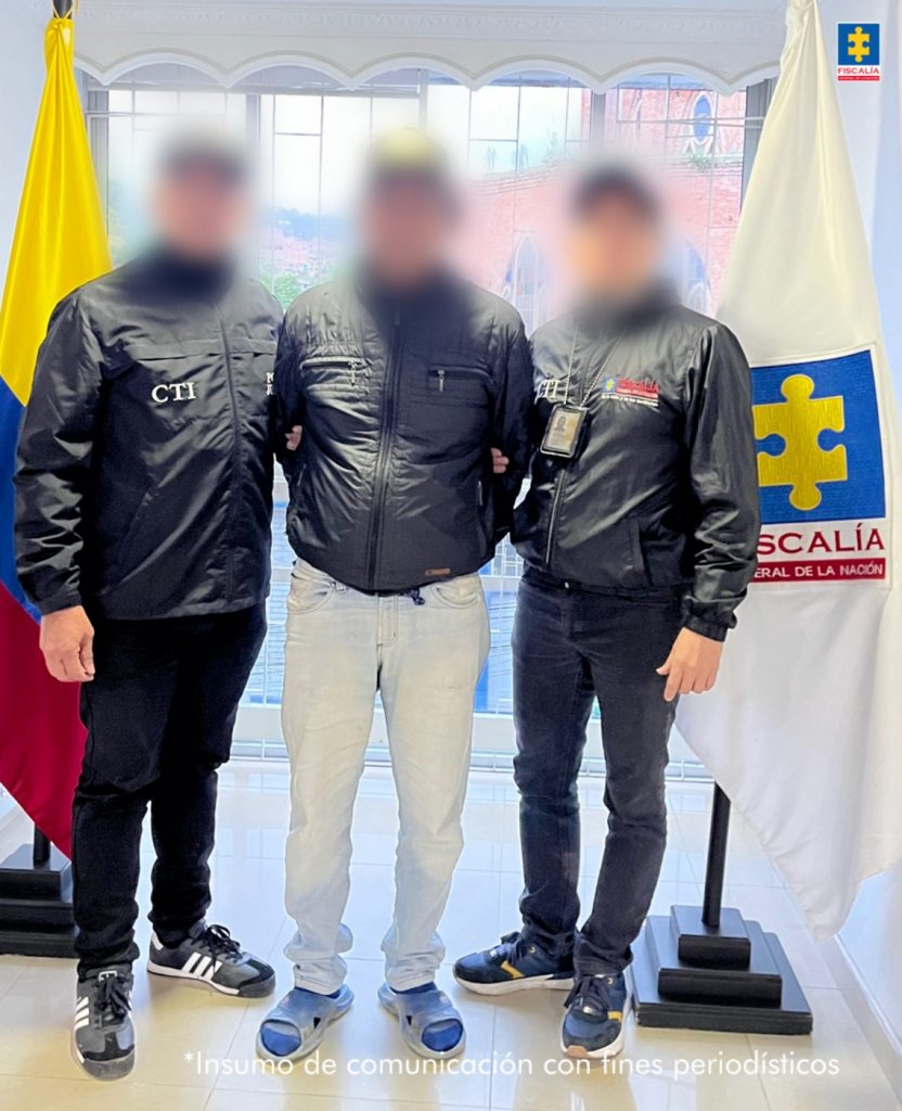 En la imagen aparece una persona de jean y chaqueta negra, entre dos uniformados del CTI.
