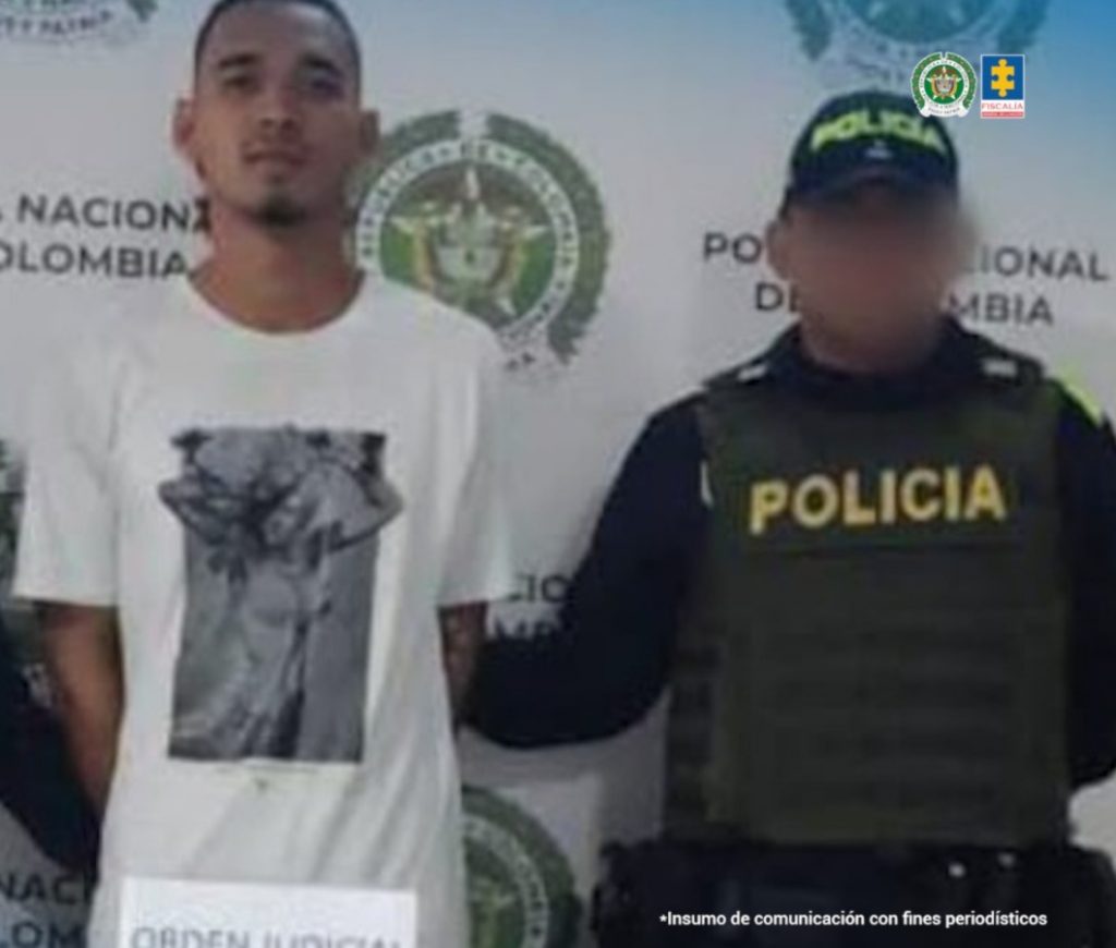 En la imagen aparece una persona de suéter blanco junto a un policía.