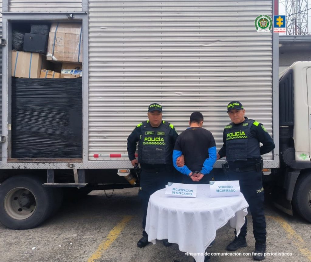 En la imagen se observa al judicializado de espalda y en medio de integrantes de la Policía Nacional. También, se visualiza el vehículo recuperado durante el procedimiento de captura.