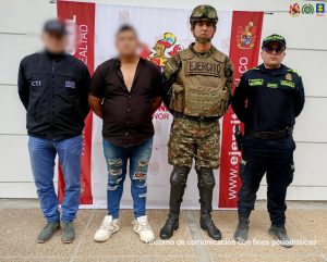 En la imagen aparecen cuatro hombres posando frente a un telón con emblemas oficiales.A la izquierda hay un hombre vestido con chaqueta negra y gorra, con las siglas CTI (Cuerpo Técnico de Investigación de la Fiscalía de Colombia) y "Policía Judicial".  A su lado está un hombre de civil, con camisa negra y pantalón de mezclilla roto, que parece ser la persona capturada.  En el centro-derecha se encuentra un militar con uniforme de camuflaje, chaleco y casco, con la palabra "EJÉRCITO" en el pecho.  A la derecha hay un policía con uniforme oscuro y gorra que dice Policía.  El fondo es un pendón institucional del Ejército Nacional de Colombia y en la parte superior se distinguen varios logos oficiales. En la esquina inferior derecha aparece un texto que dice: “insumo de comunicación con fines periodísticos”.