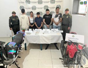 En la imagen se observa, en medio de dos integrantes de la Policía Nacional, a los procesados, uno de espaldas y el resto de frente. También se evidencian los elementos incautados en las diligencias de allanamiento y registro. 