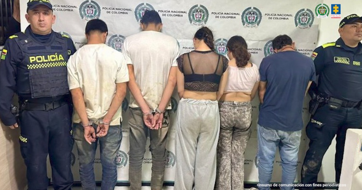 En la imagen se observa, en medio de dos integrantes de la Policía Nacional, a los cinco procesados de espaldas. 