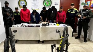 En la imagen aparecen cinco personas capturadas junto a dos uniformados de la Policía. 