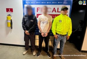 Imagen de un hombre capturado con el rostro difuminado, ubicado entre un uniformado de la Policía y un funcionario del CTI, cuyos rostros también están difuminados. Los tres están de pie frente a un fondo institucional.