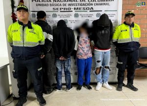 En la imagen se ve a tres personas capturadas junto a dos uniformados de la policía.