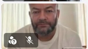 Se ve al  hombre judicializado en la audiencia de imputación de cargos. Viste una camiseta blanca y tiene barba en su rostro.