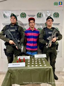 En la fotografía se aprecia de pie, con los brazos atrás, a Wilderson Rafael Loyo Ochoa. Viste camisa de manga corta con franjas azules y fucsias; así como jean azul y gorra. A sus extremos hay uniformados de la Policía Nacional. Delante de ellos hay una mesa con mantel verde oliva y sobre ella se aprecia un arma de fuego, munición y bolsas plásticas pequeñas. Detrás de ellos hay un pendón institucional de la Policía.