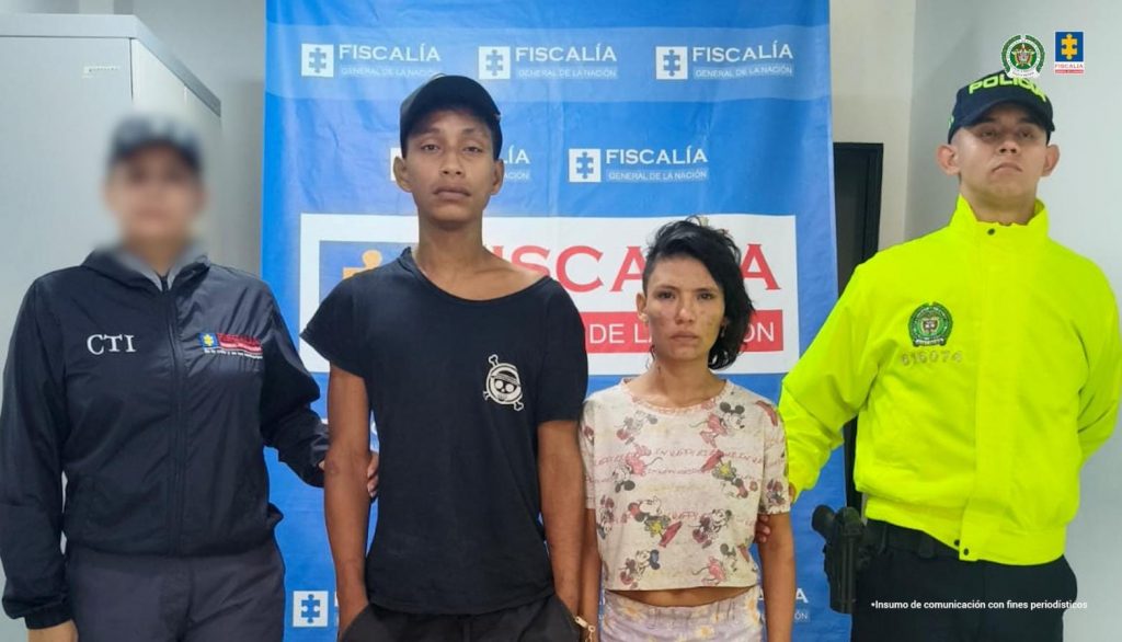Se visualiza a los capturados junto a dos uniformados de la Policía Nacional. Detrás de ellos el banner que identifica a la Fiscalía General de la Nación.