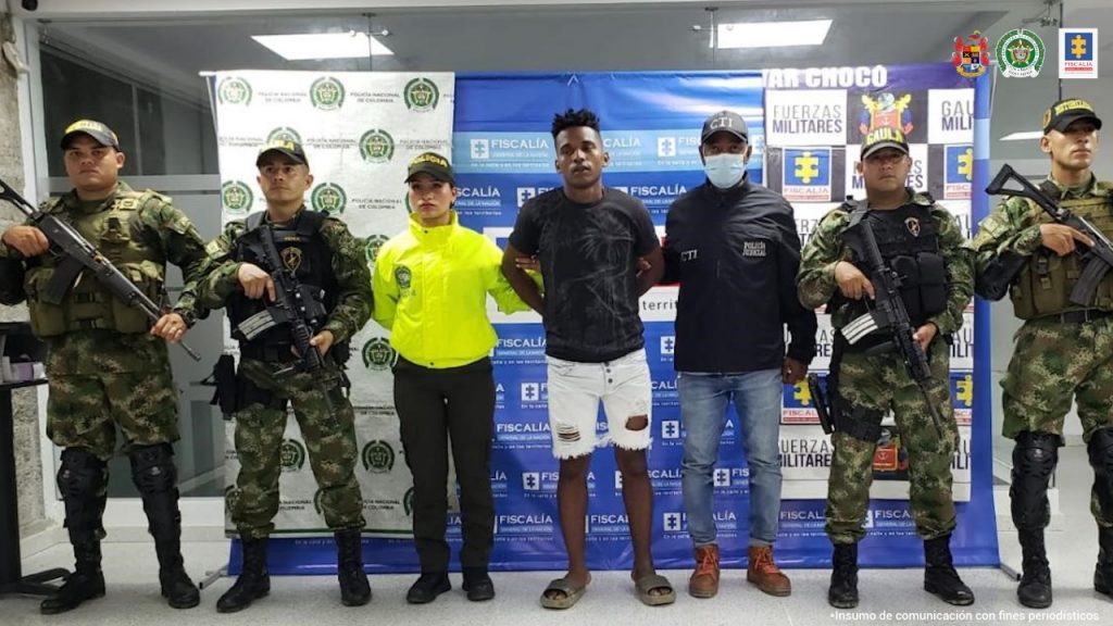 Yan Sebastián Moreno, alias Sebas, en la foto con una funcionario de la Policia Nacional, otro del CTI, y cuatro del Gaula del Ejército, atrás backin de las tres instituciones y la Fiscalía General de la Nación.