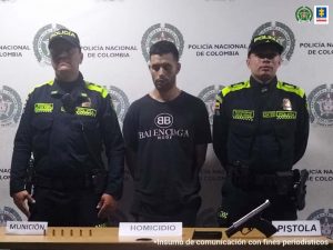 Fiscal Martha Mancera, Martha Mancera, Fiscal Mancera Se observa el capturado en el centro y a cada costado un uniformado de Policía Nacional. Atrás un pendón de Policía NAcional, al frente una mesa con el material incautado.