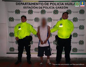 El procesado se encuentra esposado y en custodia por uniformados de la Policía Nacional. Detrás suyo un backing de la Policía.