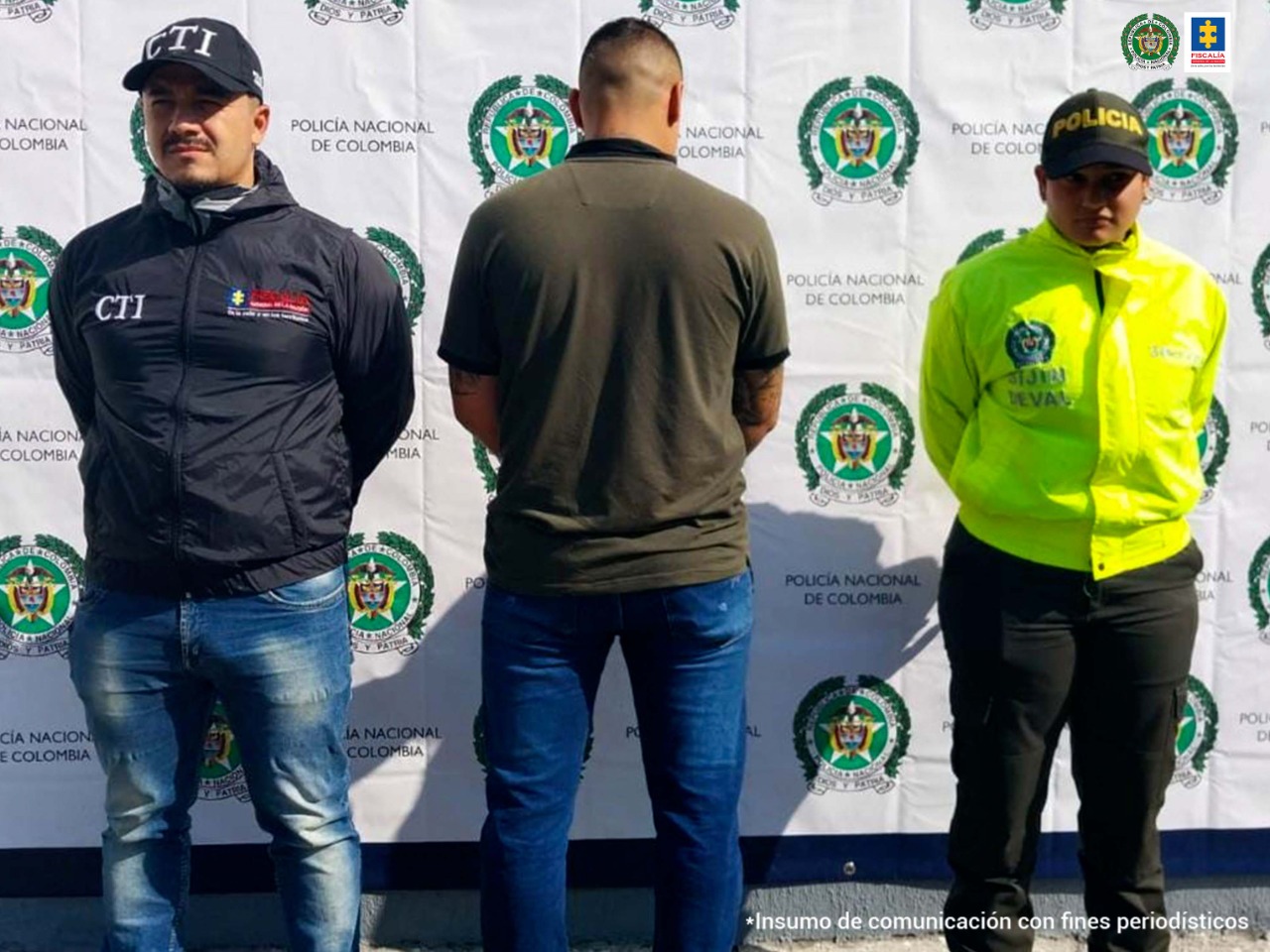 En la foto aparece de pie, de espaldas y con los brazos adelante, Yefersson Ibito Gómez, alias ‘Ibito’. Viste camisa de manga corta color verde oscuro y jean azul. A su lado derecho hay un uniformado de la Policía y a su izquierda un servidor del CTI de la Fiscalía. En la parte de atrás hay un pendón institucional de la Policía.