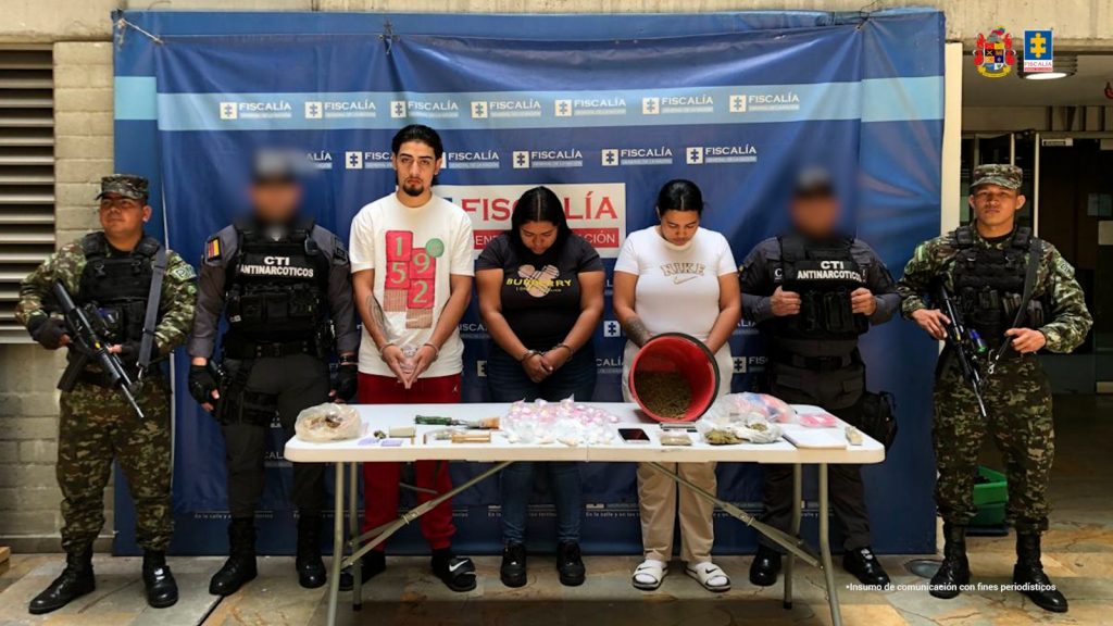 En la imagen están las dos mujeres y el hombre capturado con un servidor en medio de dos servidores del CTI y dos del Ejército Nacional, y una mesa adelante con la marihuana, la cocaína y los manuscritos de contabilidad incautados