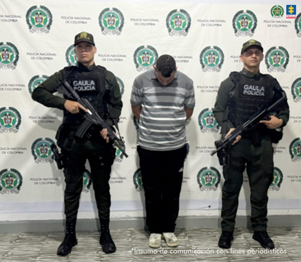 En la fotografía aparece de pie, con los brazos atrás y la cabeza agachada Yesid Londoño Hurtado. Viste camiseta de manga corta con franjas horizontales grises y blancas; pantalón negro y zapatillas blacas. A sus extremos hay uniformados de la Policía Nacional. Detrás de ellos hay un pendón institucional de la Policía.