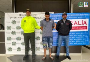 En la fotografía aparece el capturado junto a un uniformado de la Policía Nacional y un investigador del CTI. En la parte posterior se observan los banners que identifican a la Policía Nacional y a la Fiscalía General de la Nación.