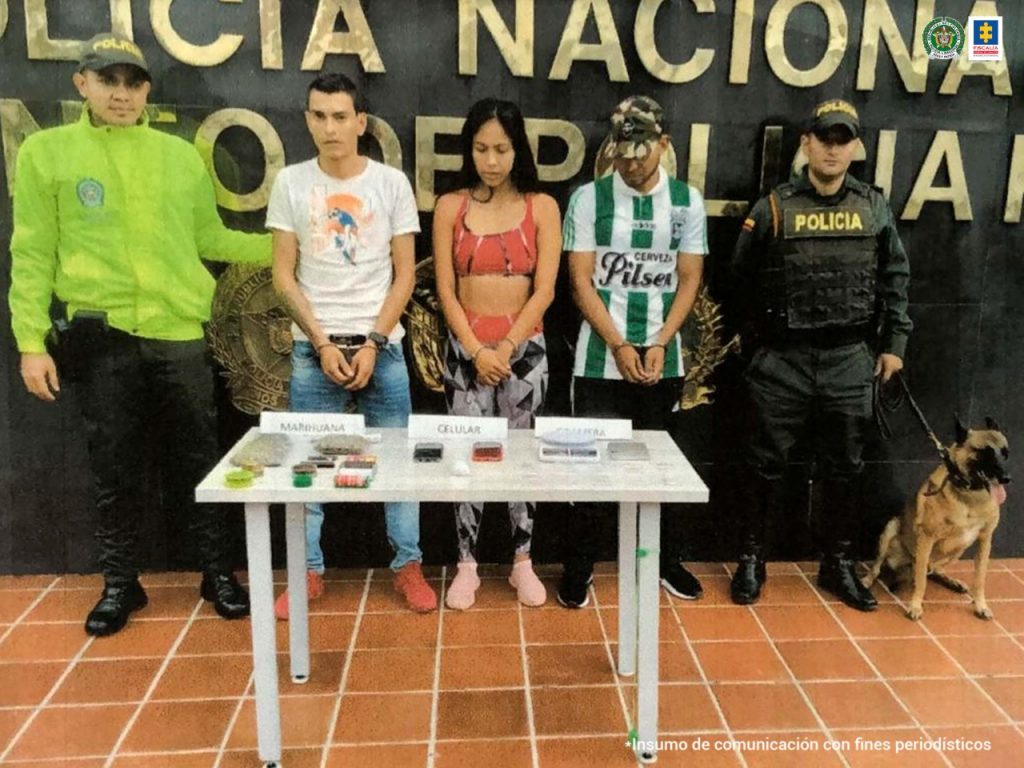 En la fotografía aparecen tres capturados, junto a personal de Policía Nacional y Fiscalía General de la Nación. En la parte posterior de la imagen se ven banners de Policía Nacional y la Fiscalía General de la Nación.