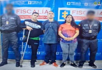  Se visualiza a los capturados junto a dos investigadores del CTI. Detrás de ellos el banner que identifica a la Fiscalía General de la Nación