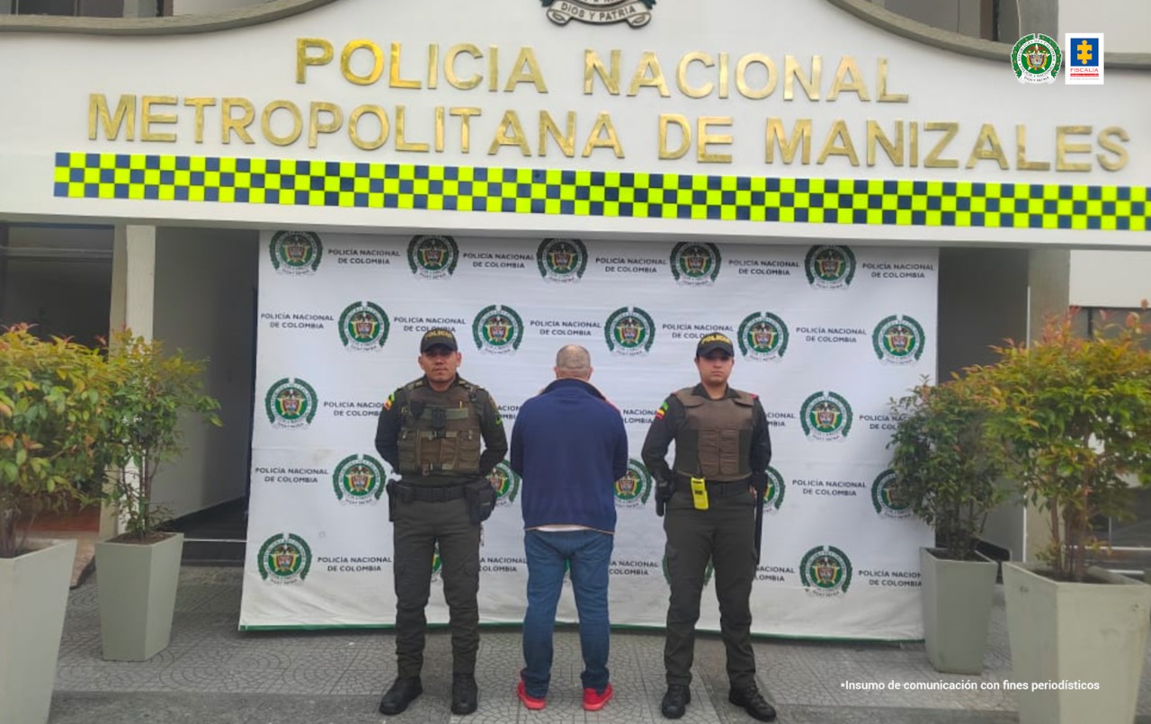 En la fotografia aparece un hombre de espaldas, que fue judicializado por el delito de homicidio. En la parte posterior se ve una imagen del banner de la Policía Nacional.