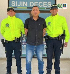 En la fotografía aparece una persona capturada, acompañado de dos uniformados de La Policía. En la parte posterior un banner con logos de la entidad