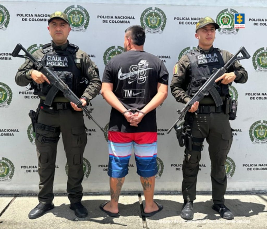 En la fotografía aparece de espaldas a la cámara, con los brazos atrás y esposado Yonier Alexander Osorio Gasca, alias El Gordo o Rosado. Viste con camiseta de color negro, manga corta y varios estampados de color blanco en la espalda; bermuda con colores rojo, azul, blanco y azul y pantuflas negras. A sus extremos hay uniformados de la Policía Nacional, Grupo Gaula. En la parte posterior hay un pendón institucional de la Policía.