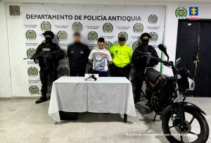 En la foto aparece Yorman Montoya en medio de servidores del CTI y la policía, junto a una motocicleta y un arma incautada..