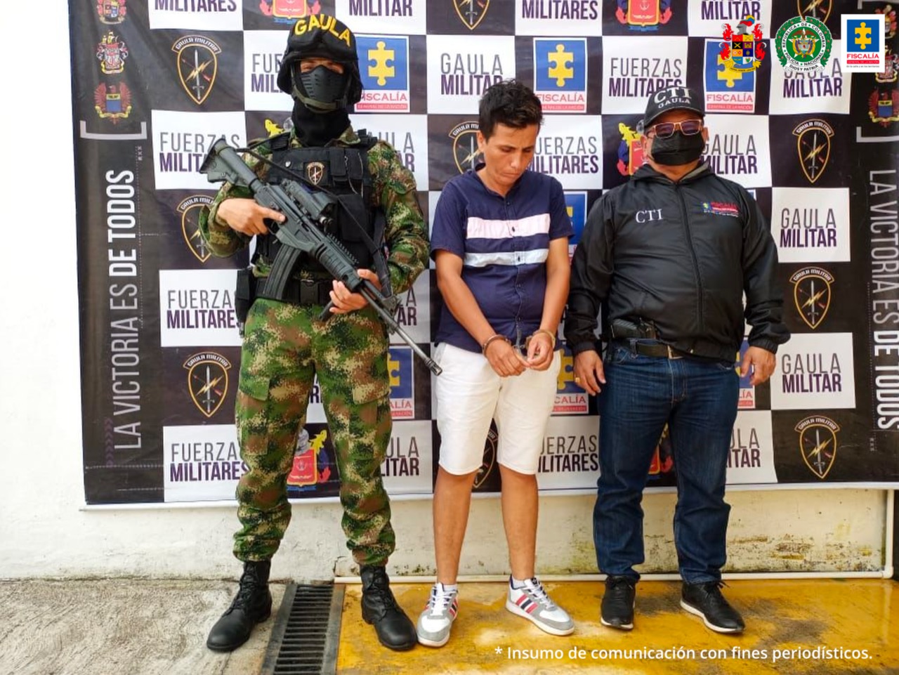 El mujer capturada está con sus manos esposadas en la parte delanmtera de su cuerpo y tiene la custoria de un hombre del CTI de la Fiscalía y un miembro del Ejército.