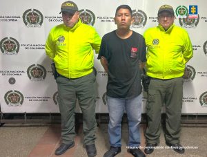 El procesado está de camiseta negra, esposado con sus manos a la espalda y custodiado por dos uniformados de la Policía Nacional.
