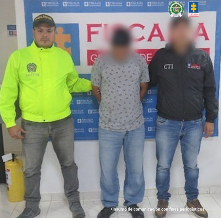 En la imagen se ve un hombre detenido de espaldas, bajo custodia de dos integrantes de la Policía Nacional.