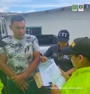 : en la imagen se ve una persona detenida a quien una integrantes de la Policía le lee sus derechos como capturado. También es acompañado por una investigadora del CTI.