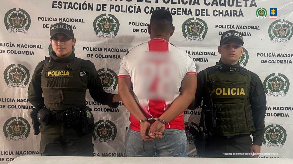 en la imagen se ve un hombre de espaldas bajo custodia de dos uniformados de la Policía Nacional.