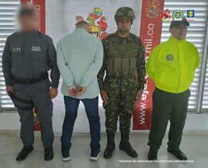 en la imagen se ve una persona detenida bajo custodia de un investigador del CTI y un uniformado de la Policía.