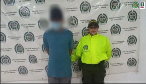 En la imagen se ve una persona detenida bajo custodia de un uniformado de la Policía Nacional.