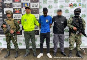En la imagen se ve una persona detenida bajo custodia de integrantes del CTI, Ejército y Policía. Detrás suyo un backing institucional.