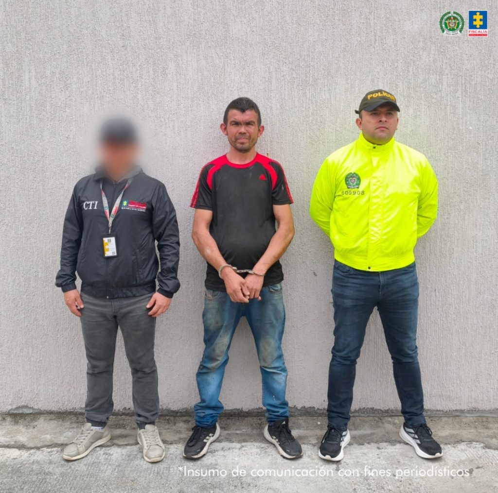 En la imagen se ve un hombre detenido bajo custodia de un investigador del CTI y un uniformado de la Policía Nacional.