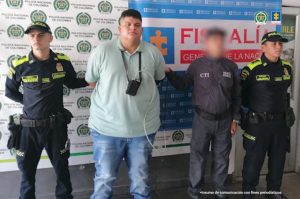 En la imagen se ve un hombre detenido bajo custodia de un investigador del CTI y uniformados de la Policía del Tolima. Detrás suyo un backing institucional.