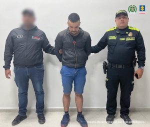en la imagen se ve un hombre detenido bajo custodia de un investigador del CTI y otro de la Policía Nacional.