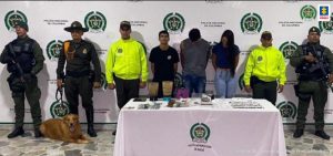 En la imagen se ven tres personas capturadas bajo custodia de varios integrantes de la Policía Nacional.