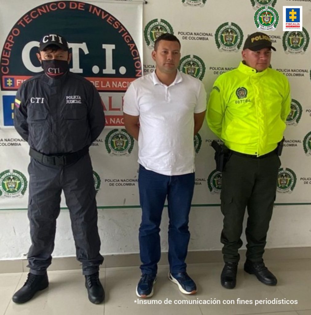 en la imagen se ve un hombre detenido bajo custodia de la Policía y el CTI. Detrás suyo un backing de cada una de las instituciones en mención.