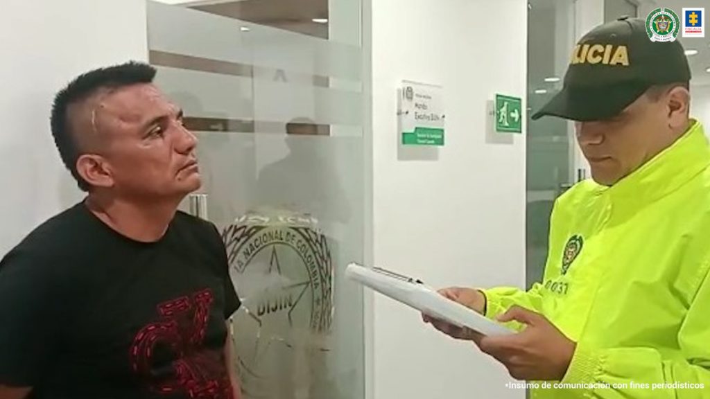 en la imagen se ve un uniformado de la Policía Nacional leyéndole los derechos del capturado a otra persona.