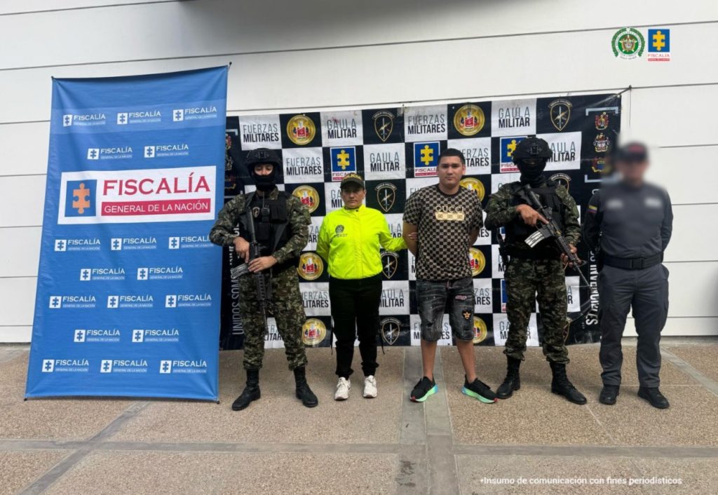 en la imagen se ve un hombre detenido bajo custodia del CTI, Policía y Ejército.DEtrás suyo backings institucionales.