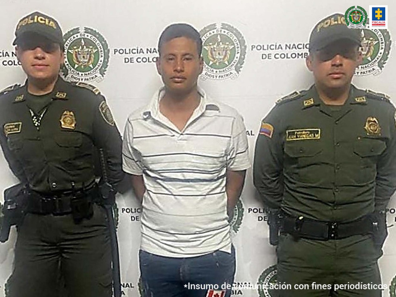 En la imagen se ven dos uniformados de la Policía Nacional con un detenido. Detrás de ellos un backing de la misma institución.