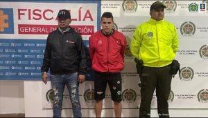 en la imagen se ve una persona detenida bajo custodia de un integrante del CTI y de la Policía Nacional. Detrás suyo backings de ambas instituciones.