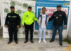 En la imagen se ve una persona detenida bajo custodia del CTI y la Policía Nacional. Detrás suyo backings institucionales.
