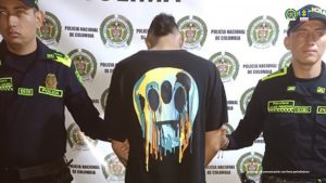 en la imagen se ve un hombre detenido en custodia de dos uniformados de la Policía Nacional.